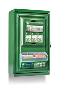 A green wall-mounted first aid cabinet containing bandages and wound care products. The cabinet includes illustrated instructions on its front, with compartments labeled "Salvequick" holding beige and pink bandages.