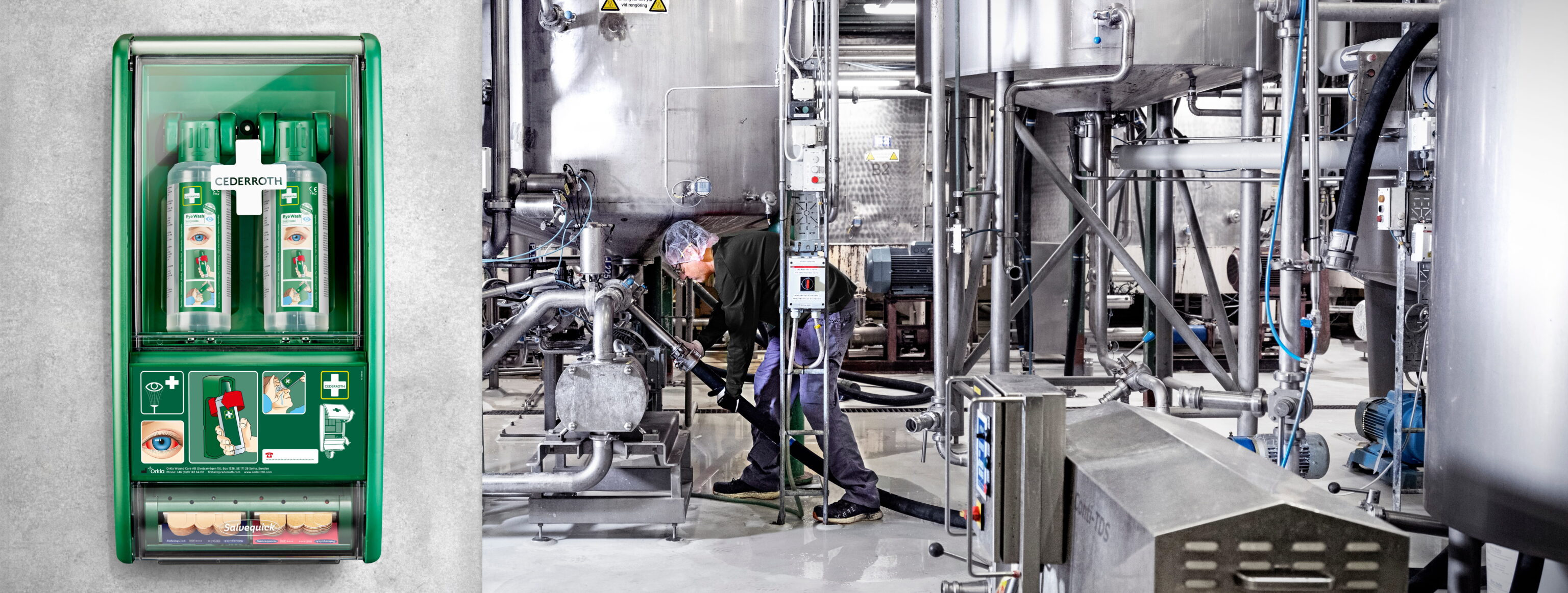Een groene EHBO-station van Cederroth met oogspoel en verbandmiddelen aan een muur, naast een industriële ruimte met grote metalen tanks en een persoon die onderhoud uitvoert.