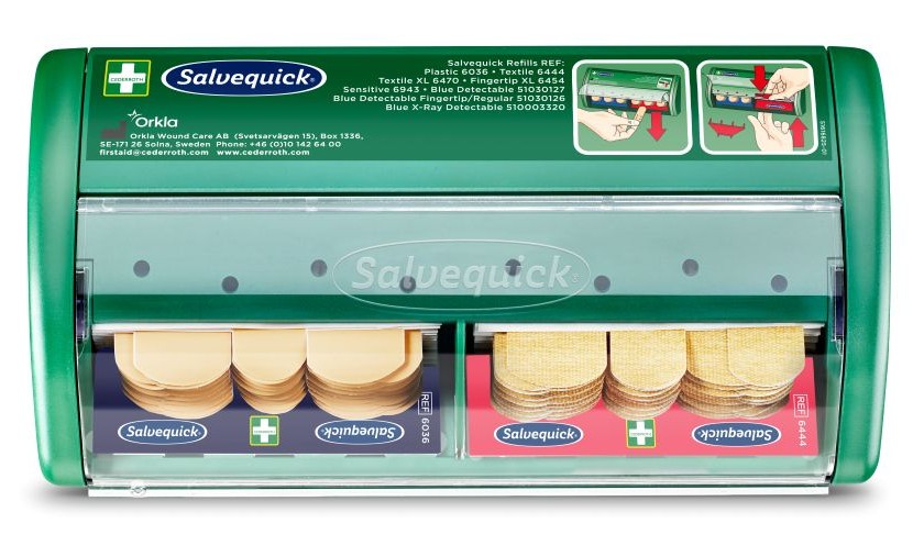 Groene Salvequick-pleisterdispenser met transparante voorkant, gevuld met pleisters in twee compartimenten. Bovenaan staan instructies voor het vervangen van pleisters en productinformatie, inclusief verschillende soorten en referentienummers.